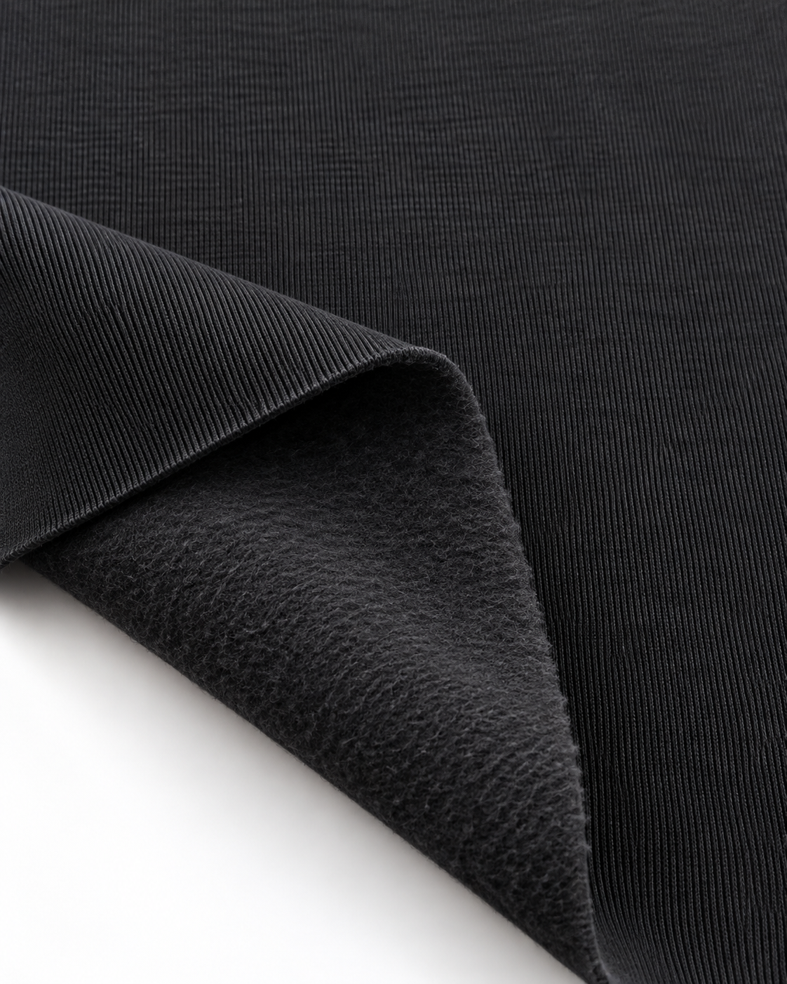 Black brushed fleece fabric showing a smooth outer surface and soft fleece on the inside.