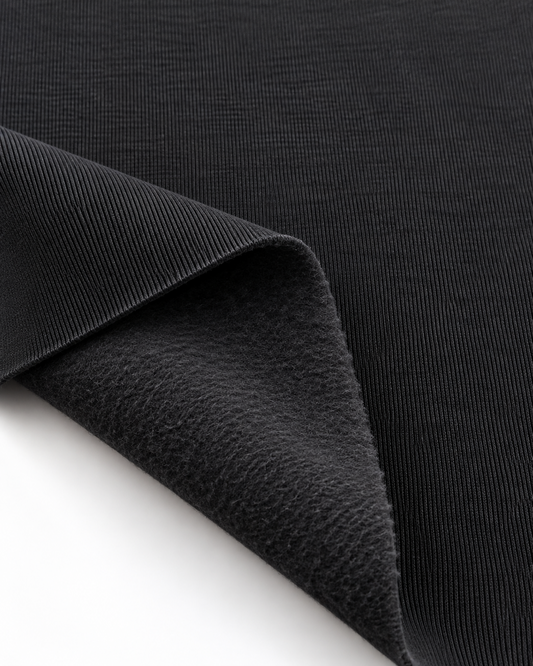 Black brushed fleece fabric showing a smooth outer surface and soft fleece on the inside.