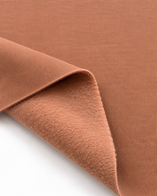 Mocha Mousse brushed fleece fabric showing a smooth outer surface and soft fleece on the inside.